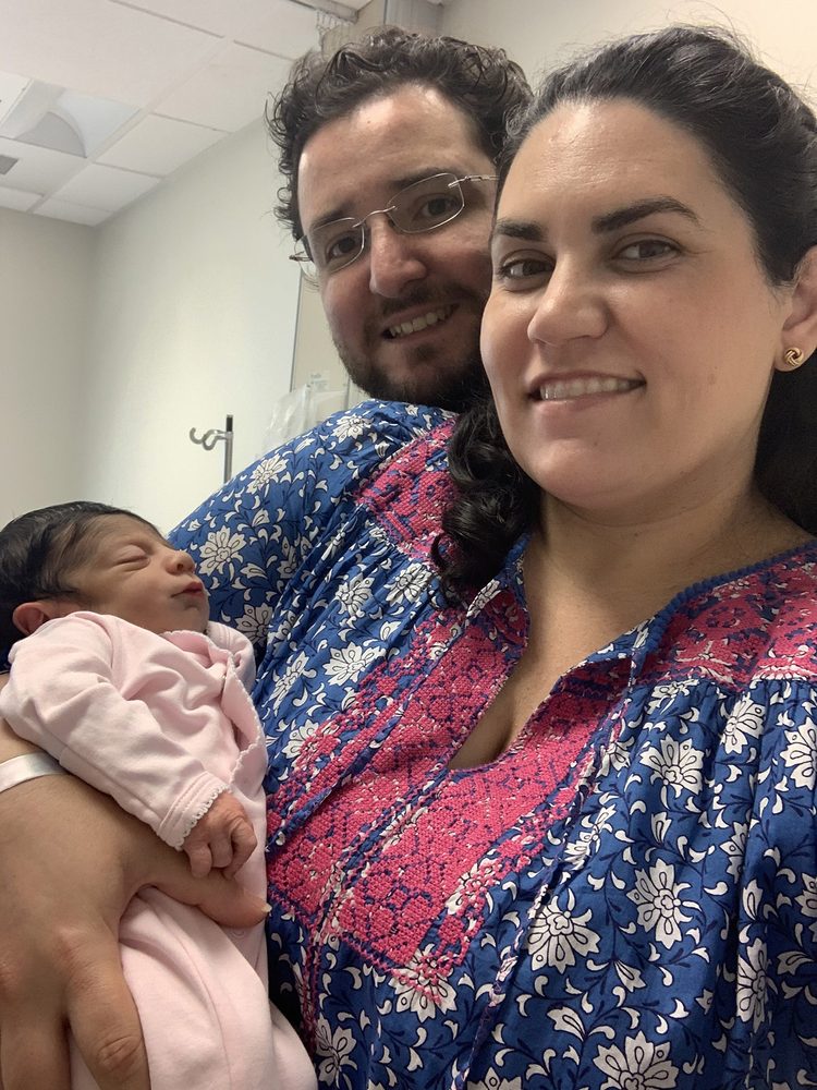 New parents smiling as they hold their newborn daughter