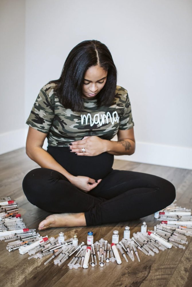 An expecting mother seated with the fertility syringes and vials from her journey arranged around her